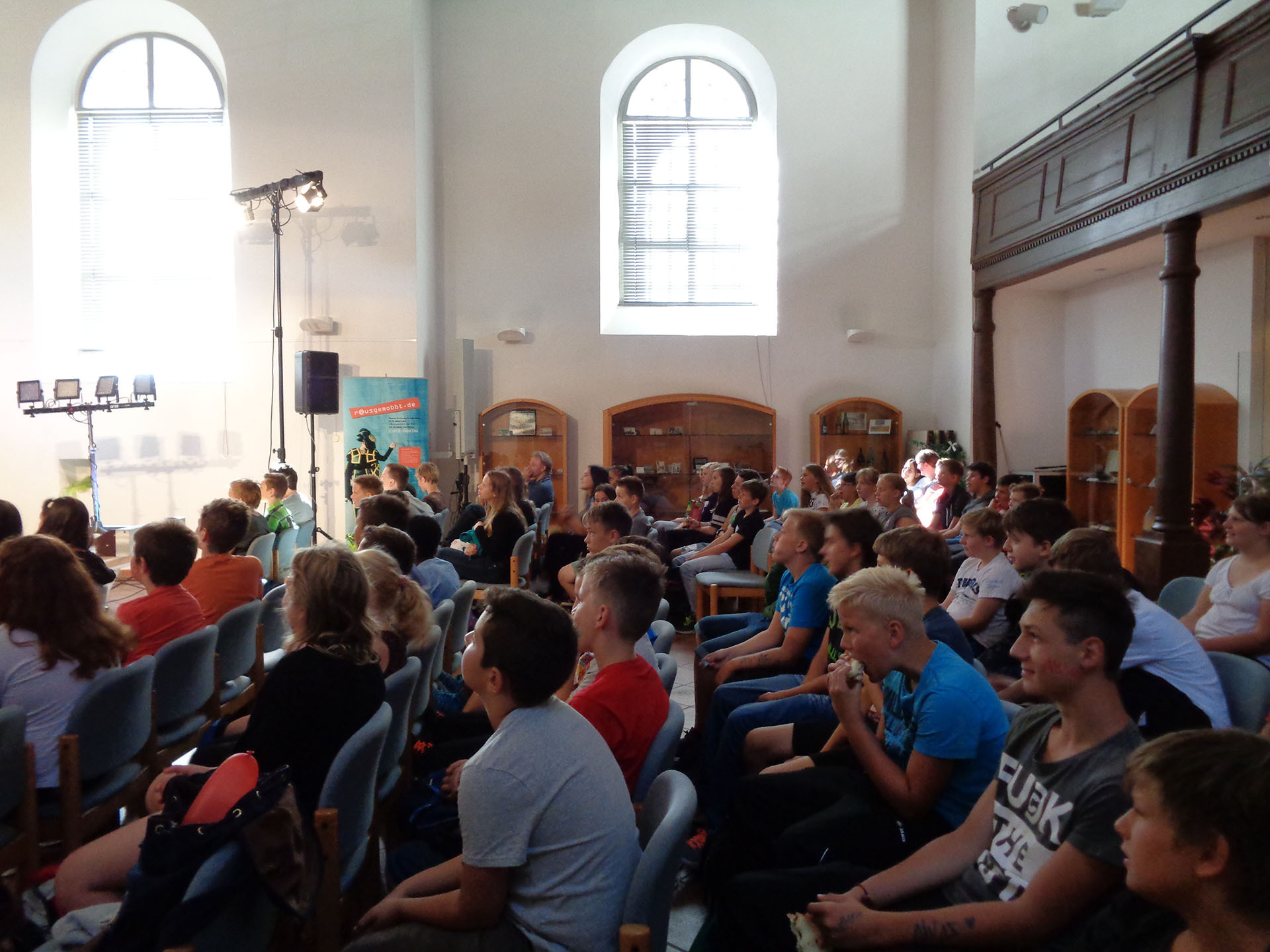 Kinder und Jugendliche nehmen in einem hellen Raum an einer VIDETO-Veranstaltung zur Gewaltprävention und Demokratieförderung teil, die demokratische Werte und Toleranz fördert.