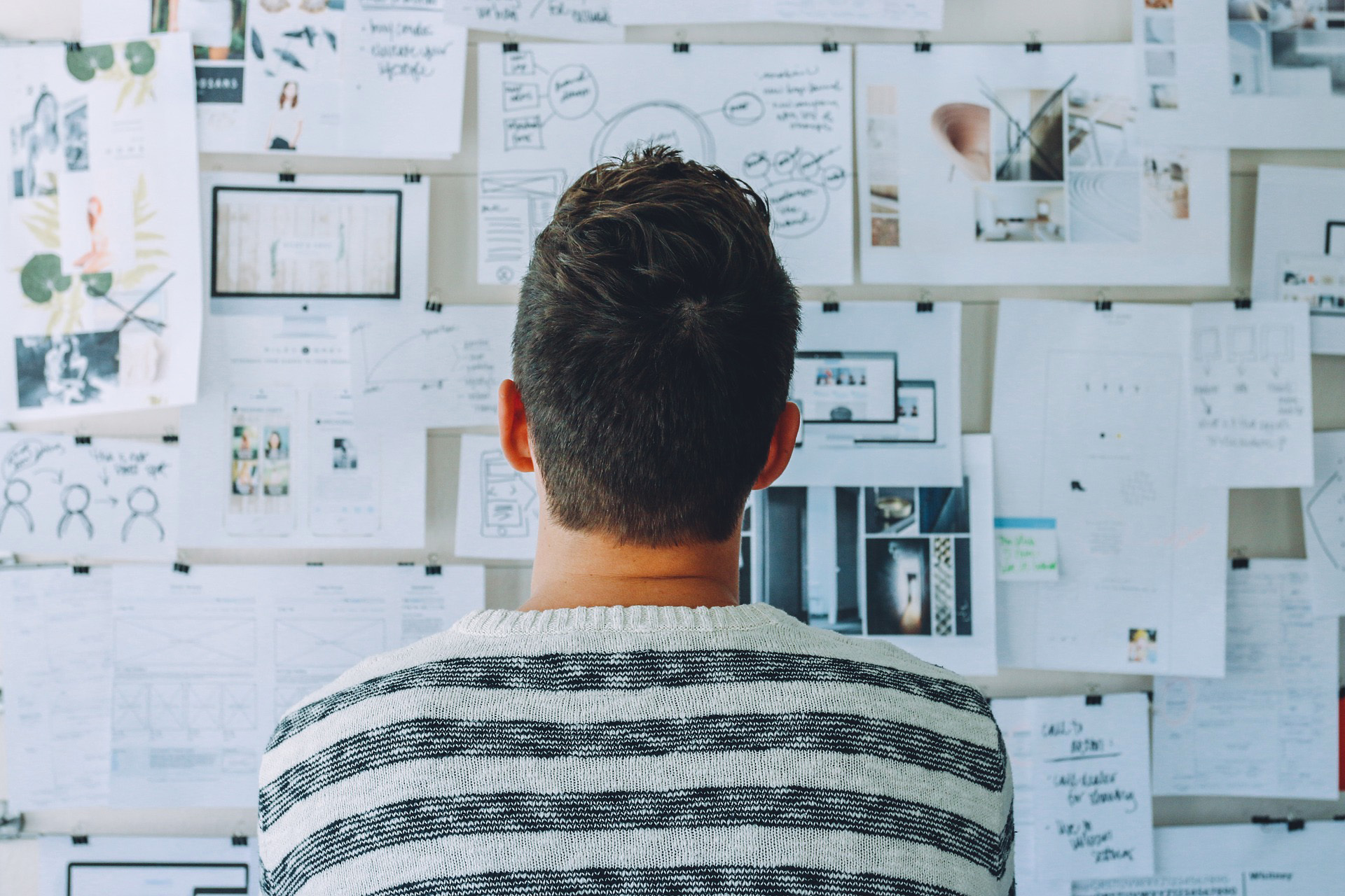 Ein Mann von hinten blickt auf eine Wand mit Notizen, Skizzen und Bildern, die demokratisches Engagement und gemeinsame Projektarbeit symbolisieren – ein Bild, das die Arbeit von VIDETO zur Stärkung toleranter Gesellschaften widerspiegelt.