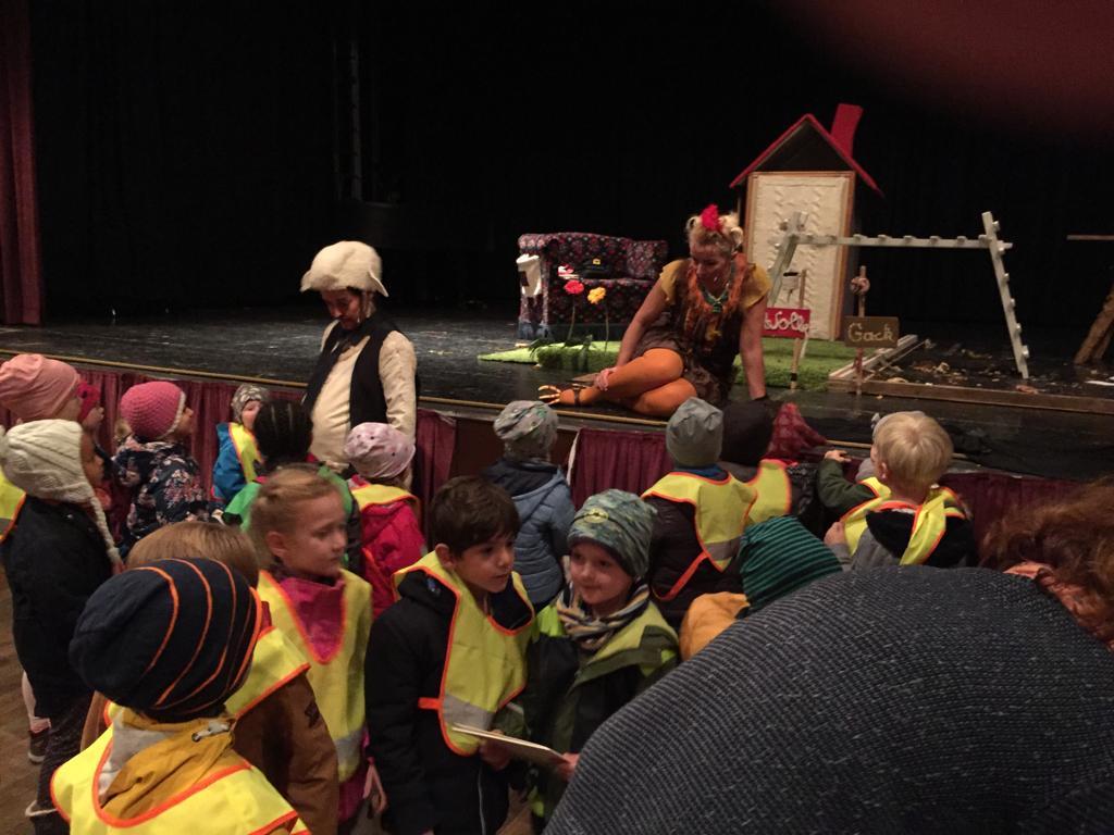 Kinder in gelben Sicherheitswesten schauen einer Theateraufführung zu, bei der Schauspielerinnen und Schauspieler ein Stück zum Abbau von Vorurteilen präsentieren – ein VIDETO-Projekt zur Förderung von Toleranz und demokratischem Miteinander.