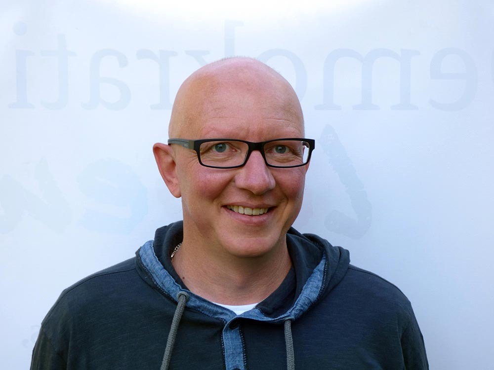 Martin Kaiser, ein lächelnder Mann mit Glatze und Brille in einem dunklen Hoodie, ist Teil des VIDETO-Projekts, das demokratisches Engagement, Vielfalt und Toleranz in den Kommunen Bad Camberg, Brechen, Hünfelden und Selters fördert.